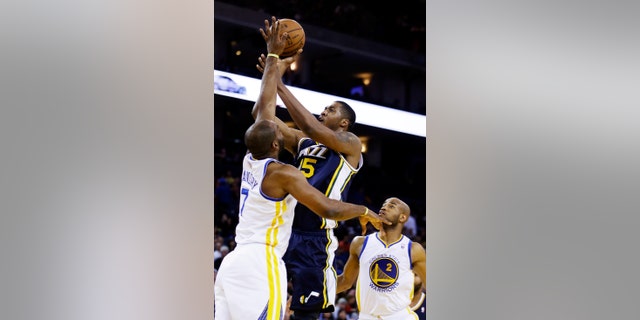 Utah Jazz's Derrick Favors (15) shoots over Golden State Warriors' Carl Landry during the first half of an NBA basketball game, Sunday, April 7, 2013, in Oakland, Calif. (AP Photo/Ben Margot)