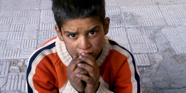 FILE - This Monday, Jan. 6, 2014 activist file photo provided by the group Palestinians of Syria, shows a child sitting on a broken sidewalk after hearing that Syrian authorities would allow civilians to leave in the Palestinian neighborhood of Yarmouk in Damascus, Syria. The chief of the United Nations relief agency supporting Palestinian refugees, Filippo Grandi, said Tuesday he is "deeply disturbed and shaken" by the despair and destruction he'd seen in the besieged Yarmouk refugee camp in the Syrian capital. Many need food and medical treatment immediately, Grandi said in a statement released Tuesday. (AP Photo/Palestinians of Syria, File)