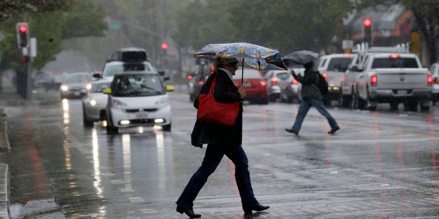 Pedestrians shield themselves from the rain with umbrellas Friday, April 6, 2018, in Santa Rosa, Calif.