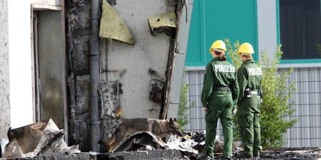 FILE - In this Aug. 26, 2015 file picture police officers and their sniffer dog examine the ruins of a burned out gym in Nauen, Germany. A German court has convicted a far-right politician for burning down the  building intended as housing for refugees. The Potsdam court sentenced 29-year-old Maik Schneider, a member of the National Democratic Party, to eight years imprisonment for arson Thursday. Feb. 9, 2017.   ( Nestor Bachmann/dpa via AP,file)