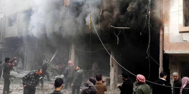 This photo released on Sunday, Dec 13, 2015 by the Douma Revolution News Network on their Facebook page, shows Syrians trying to extinguish fire that was caused by Syrian government aerial bombardment on the Damascus suburb of Douma, Syria. Syrian government helicopter gunships have struck a suburb of the capital, Damascus, a day after airstrikes on nearby areas killed more than 40 people, opposition activists said. (Douma Revolution via AP)