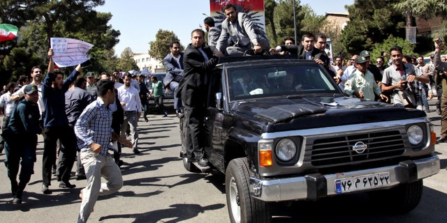 A protester, left, approaches President Hassan Rouhani's car leaving Mehrabad airport after his arrival from the U.S. in Tehran, Iran, Saturday, Sept. 28, 2013. Iranians from across the political spectrum hailed Saturday the historic phone conversation between President Barack Obama and his Iranian counterpart Rouhani, reflecting wide support for an initiative that has the backing of both reformists and the country's conservative clerical leadership. Despite the broad-based praise, the hard-liners opposed to any improved contact with Washington made their objections clear at Rouhani's arrival in Tehran. Several dozen protesters chanted "Death to America" and tried to block Rouhani's motorcade.(AP Photo/Ebrahim Noroozi)