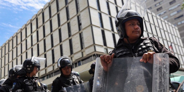 MEXICO CITY, MEXICO - JUNE 26: Mexican police stand guard outside the U.S. emabassy as a group of protesters passes by on June 26, 2012 in Mexico City, Mexico. Students have been protesting throughout the city calling for transparency and fairness as Mexicans go to the polls to elect a new president this Sunday, July 1. (Photo by John Moore/Getty Images)