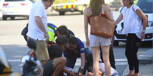 An injured person is treated in Barcelona, Spain, Thursday, Aug. 17, 2017 after a white van jumped the sidewalk in the historic Las Ramblas district, crashing into a summer crowd of residents and tourists and injuring several people, police said. (AP Photo/Oriol Duran)