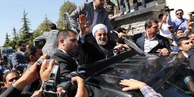 Iranian president Hassan Rouhani waves to supporters as his motorcade draws out of Tehran's Mehrabad Airport upon his arrival from New York, on September 28, 2013