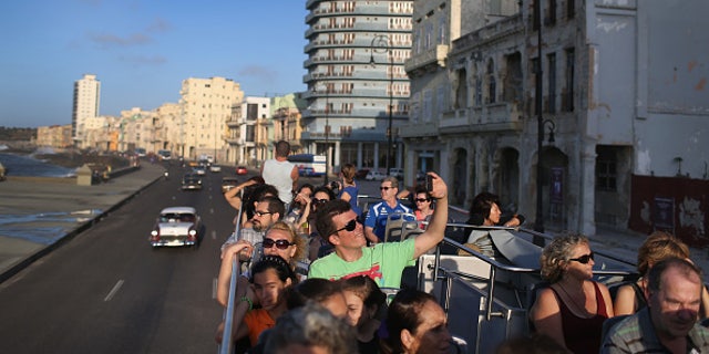 Tourists take in the sites from a double decker tour bus of Havana.