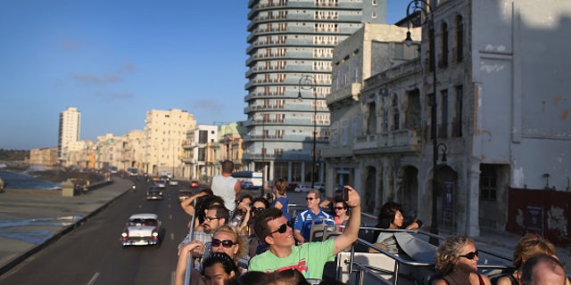 Tourists take in the sites from a double decker tour bus of Havana.