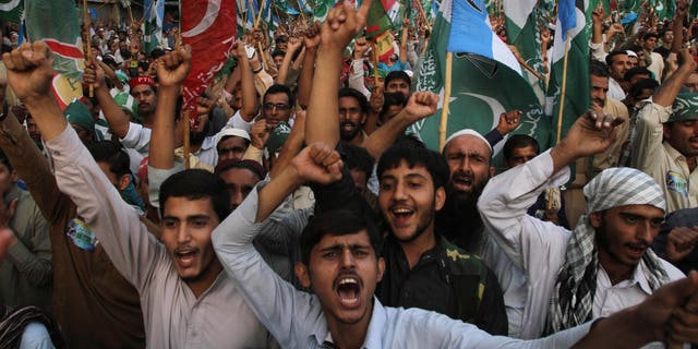 Supporters of the Pakistani religious party Jammat-e-Islami and Tehreek-e-Insaf party, headed by cricketer-turned politician Imran Khan, hold up their parties' flags and chant slogans during a rally against U.S. drone strikes in Pakistani areas, in Karachi, Pakistan, Sunday, Nov. 24, 2013. (AP Photo/Fareed Khan)