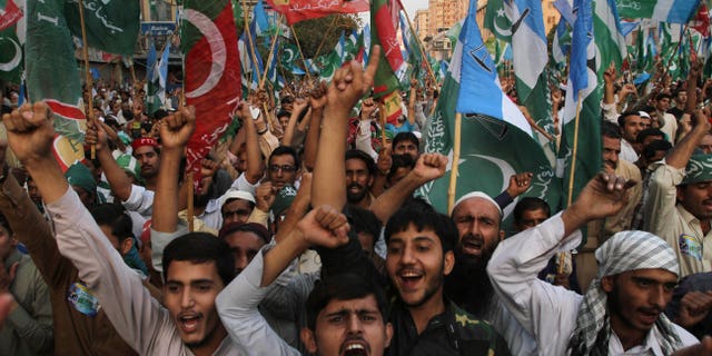 Supporters of the Pakistani religious party Jammat-e-Islami and Tehreek-e-Insaf party, headed by cricketer-turned politician Imran Khan, hold up their parties' flags and chant slogans during a rally against U.S. drone strikes in Pakistani areas, in Karachi, Pakistan, Sunday, Nov. 24, 2013. (AP Photo/Fareed Khan)