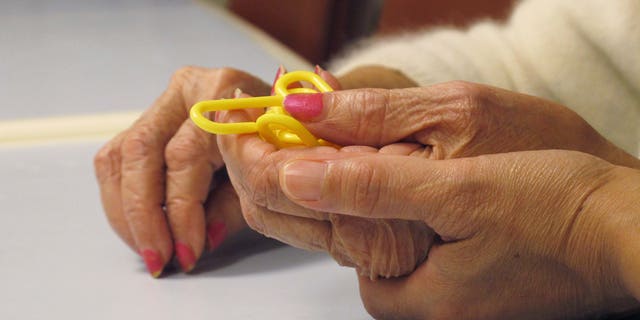 In this Sept. 20, 2012 photo, a physical therapist guides a dementia patient through a puzzle at the Hebrew Home at Riverdale in the Bronx borough of New York. The Hebrew Home has a program that provides care and activity overnight for dementia victims with sleep problems. (AP Photo/Jim Fitzgerald)