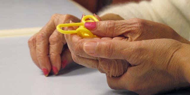 In this Sept. 20, 2012 photo, a physical therapist guides a dementia patient through a puzzle at the Hebrew Home at Riverdale in the Bronx borough of New York. The Hebrew Home has a program that provides care and activity overnight for dementia victims with sleep problems. (AP Photo/Jim Fitzgerald)