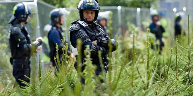 Police officers in body armour line the perimeter fence of the test drill site operated by British energy firm Cuadrilla Resources in Balcombe, southern England, on August 20, 2013, as anti-fracking activists hold a protest camp nearby.