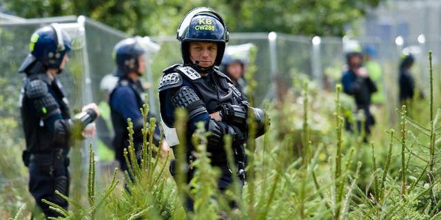 Police officers in body armour line the perimeter fence of the test drill site operated by British energy firm Cuadrilla Resources in Balcombe, southern England, on August 20, 2013, as anti-fracking activists hold a protest camp nearby.