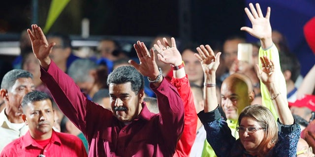 Venezuela's President Nicolas Maduro and his wife Cilia Flores wave to supporters at the presidential palace in Caracas, Venezuela, Sunday, May 20, 2018