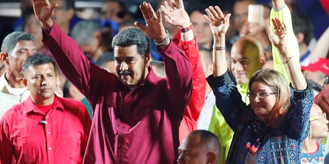 Venezuela's President Nicolas Maduro and his wife Cilia Flores wave to supporters at the presidential palace in Caracas, Venezuela, Sunday, May 20, 2018