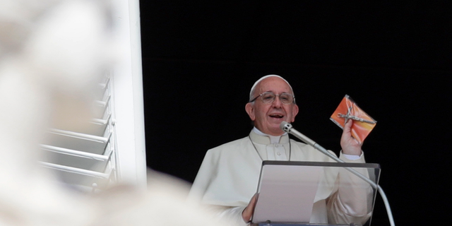 Pope Francis shows a crucifix during the Angelus noon prayer he delivers from the window of his studio overlooking St. Peter's Square at the Vatican, Sunday, Sept. 16, 2018. Tens of thousands of faithful have been treated to gifts from the pontiff, tiny crucifixes, distributed by nuns, refugees and some of Rome's homeless and poor after the pope’s traditional Sunday appearance to pilgrims and tourists in the square. (AP Photo/Alessandra Tarantino)