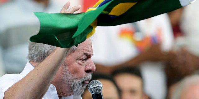 Brazil's former President Luiz Inacio Lula da Silva, holds a Brazilian flag, while speaking during a rally of Social Movements for Democracy, in a camp set up by supporters of President Dilma Rousseff in Brasilia, Brazil, Saturday, April 16, 2016. The lower chamber of Brazil's Congress on Friday began a debate on whether to impeach Rousseff, a question that underscores deep polarization in Latin America's largest country and most powerful economy. The crucial vote is slated for Sunday. (AP Photo/Eraldo Peres)