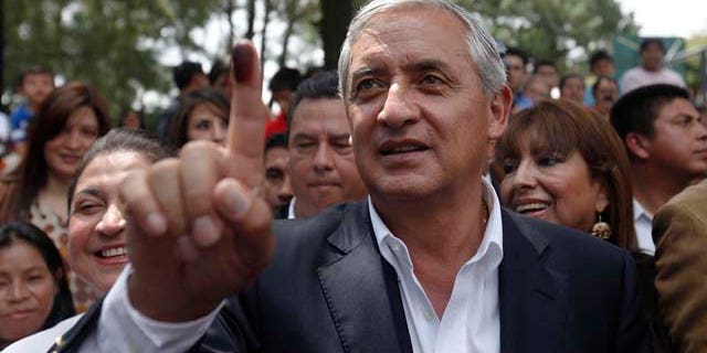 Guatemala's presidential candidate of the Patriotic Party Otto Perez Molina, shows his ink-stained thumb after casting his vote at a polling during the country's presidential elections in Guatemala City, Sunday, Sept. 11, 2011. (AP Photo/Moises Castillo)