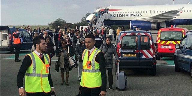People are evacuated from a British Airways plane on the tarmac of Charles de Gaulle airport, in Paris, Sunday, Sept. 17, 2017.