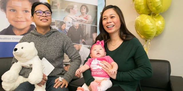 Romeo Crisostomo and mother Romeila Son sit with their healthy daughter, Eiko, who had surgery as a fetus to correct a spinal defect.