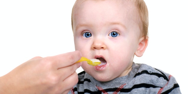 Baby being fed rice cereal.