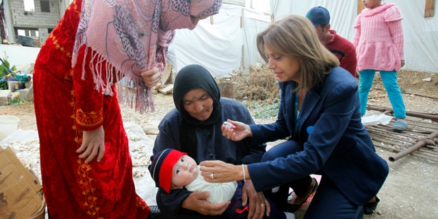 A UNICEF representative in Lebanon administers a polio vaccine to a baby at a Syrian refugee camp near Zahle town in the Bekaa Valley November 8, 2013. (REUTERS/Sharif Karim)