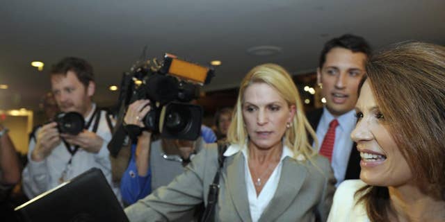 Republican presidential candidate, Rep. Michele Bachmann, R-Minn., right, is rushed past the news media as she departs a National Press Club luncheon in Washington, Thursday, July 28, 2011. . (AP Photo/Cliff Owen)