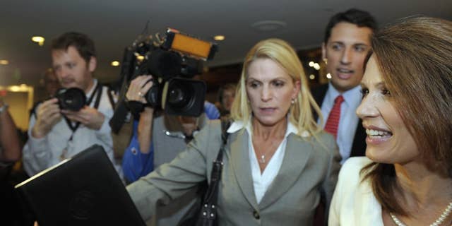 Republican presidential candidate, Rep. Michele Bachmann, R-Minn., right, is rushed past the news media as she departs a National Press Club luncheon in Washington, Thursday, July 28, 2011. . (AP Photo/Cliff Owen)
