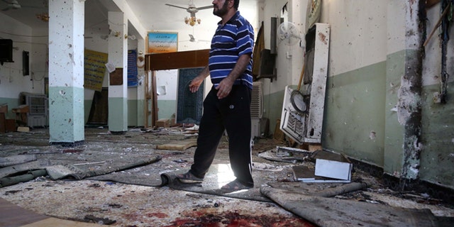 Aug. 25, 2014: A man walks past blood stains on the floor of the Imam Ali mosque after a suicide bomb attack in New Baghdad, Iraq.