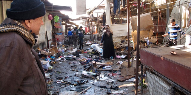 Dec. 25, 2013: A man looks at the site of bomb attack at a marketplace in Baghdad's Doura District.