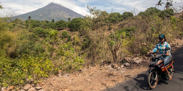 A villager rides by, with Mount Agung seen in the background, in Karangasem, Bali, Indonesia, Sept. 24, 2017.