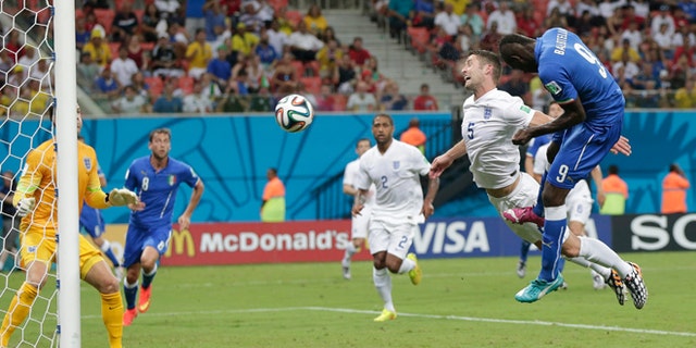 June 14, 2014: Italy's Mario Balotelli (9) heads the ball past England's Gary Cahill (5) and goalkeeper Joe Hart, left, to score Italy's second goal during the group D World Cup soccer match between England and Italy at the Arena da Amazonia in Manaus, Brazil.