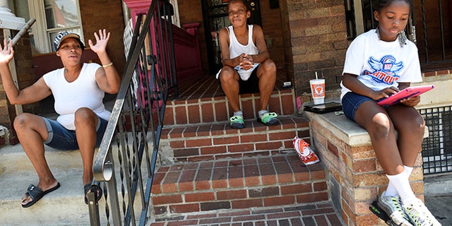 Neighborhood residents Mary Johnson (C), her niece Erika Johnson (L) and her granddaughter Ayanna Herbert, 9, spend time near 2100 Homewood Avenue before the "Huddle Up on the Wood" event and Cease Fire Community Jubilee during the 72-hour community-led Baltimore Ceasefire against gun violence in Baltimore, Maryland, U.S. August 4, 2017. REUTERS/Sait Serkan Gurbuz - RTS1AFF8