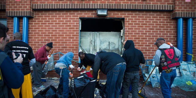 Maryland state troopers stand guard as residents clean up, Tuesday, April 28, 2015, after an evening of riots following the funeral of Freddie Gray on Monday, in Baltimore. (AP Photo/Evan Vucci)