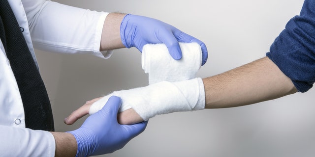 Pediatrician wraps wrist of an unidentified student.