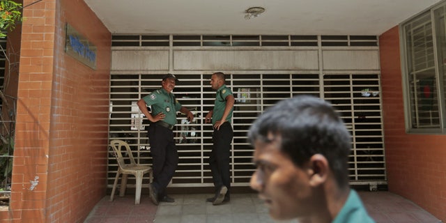 April 26, 2016: Bangladeshi policemen stand guard at the entrance to the building where two people were stabbed to death by unidentified assailants in Dhaka, Bangladesh.