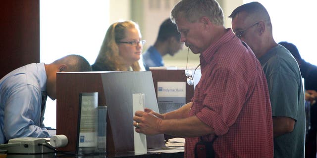 PASADENA, CA - JULY 14:  Customers (R) carry out their transactions with tellers after waiting in line with hundreds of other nervous customers to get into an IndyMac Bank, open for the first time since the July 11 federal government takeover of the thrift, on July 14, 2008 in Pasadena, California. IndyMac, which was already in trouble because of it's subprime mortgages with people with bad or no credit history, was shut down three hours early on a Friday and remained closed over the weekend after customers withdrew $1.9 billion. Regulators say it is the second-largest bank failure ever in the US. As all 33 IndyMac branches reopen, customers with home-equity credit lines will reportedly find their accounts frozen while transactions involving deposit accounts will be conducted as normal under the name, IndyMac Federal Bank. Over the weekend, the Federal Reserve also worked on shoring up lenders Fannie Mae and Freddie Mac which control almost half of the national mortgage debt and are in danger of collapse as well.  (Photo by David McNew/Getty Images)