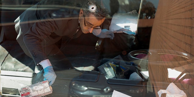 An investigator inside the truck with bullet holes in the windshield.