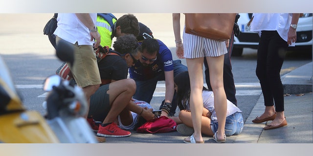 An injured person is treated in Barcelona, Spain, Thursday, Aug. 17, 2017 after a white van jumped the sidewalk in the historic Las Ramblas district, crashing into a summer crowd of residents and tourists and injuring several people, police said. (AP Photo/Oriol Duran)