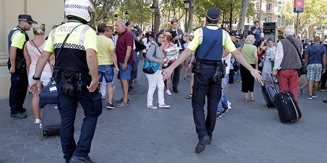 Police officers tell members of the public to leave the scene on a street in Barcelona, Spain, Thursday, Aug. 17, 2017.