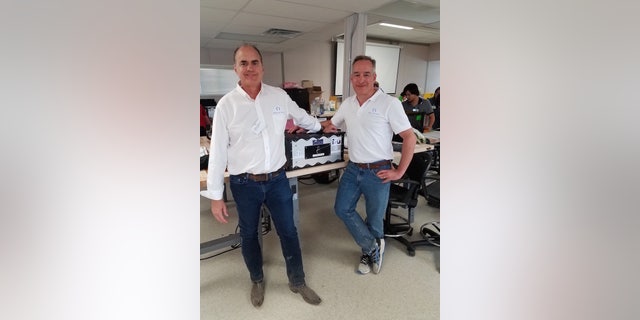 Barnett and Matossian pose with the Solstar Communicator, inside they house the modem and router that connects to the internet in space.