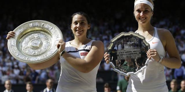 July 6, 2013: Marion Bartoli of France, left, holds her winners trophy as she stands alongside Sabine Lisicki of Germany during the trophy ceremony after the Women's singles final match at the All England Lawn Tennis Championships in Wimbledon, London. (AP)