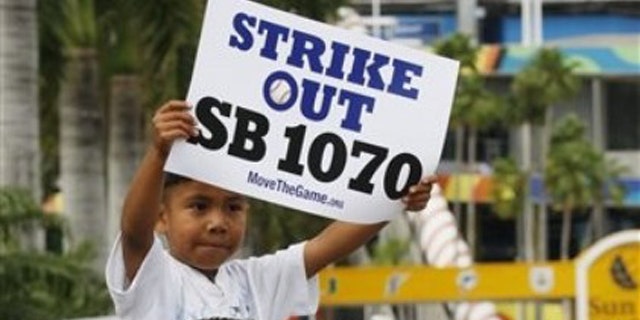 Elias Perez, 5, sits on the shoulders of Gerardo Reyes of Immokalee, Fla. , as they protest the Arizona Immigration Law SB 1070 outside Sun Life Stadium, before a baseball game between the Florida Marlins and the Arizona Diamondbacks, Monday, May 17, 2010 in Miami. (AP)