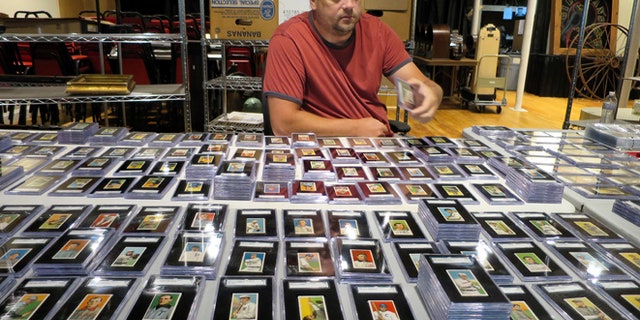In this Aug. 25, 2014 photo, Troy Thibodeau, from Saco River Auction Co., examines a collection of more than 1,400 baseball cards from 1909, 1910, and 1911 in Biddeford, Maine. The collection will be auctioned off starting in January 2015. (AP/David Sharp)
