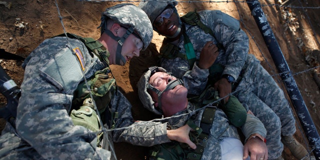 Pvts. Sean Christopher Welliver, left, and John Hubbard, right, drag fellow Pvt. William Weaver (C) through an obstacle course as part of a first aid training exercise.