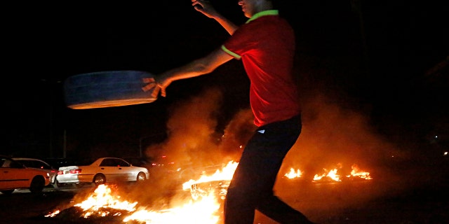 A man burns tires during a protest demanding services and jobs in Basra, 340 miles southeast of Baghdad, Iraq, July 13, 2018.