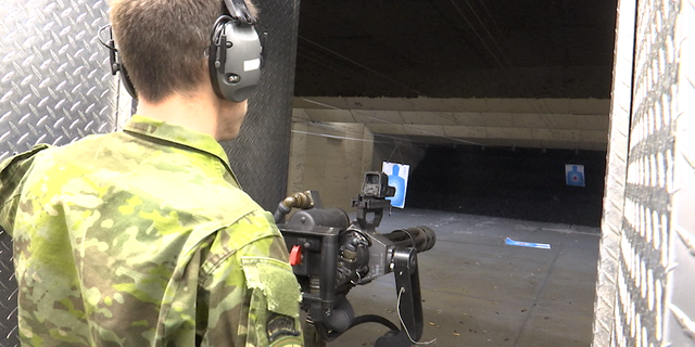 A staffer positions and readies the minigun, a machine gun with a high rate of fire, for use at the target range