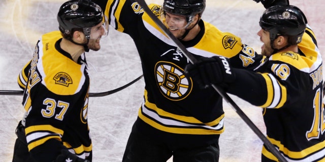 Boston Bruins center Patrice Bergeron, left, is congratulated by teammates David Krejci, center, and Nathan Horton, right, after his goal in the final minute of the third period, which tied the game 4-4 forcing overtime against the Toronto Maple Leafs, in Game 7 of their NHL hockey Stanley Cup playoff series in Boston, Monday, May 13, 2013. (AP Photo/Charles Krupa)