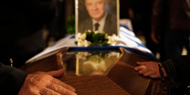 People touch the coffin of the former Cyprus President Glafcos Clerides, whose body lies in state at the Orthodox Christian Church of the Lord's Wisdom in capital Nicosia, Cyprus, Monday, Nov. 18, 2013. The politician's state funeral Tuesday will be held with honors befitting a sitting president and will be a public holiday. He was 94. (AP Photo/Petros Karadjias)