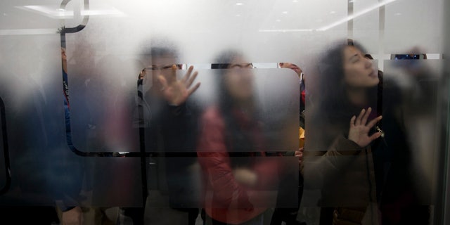 People try to get a view of U.S. Secretary of State John Kerry as he arrives for a tour of the Foton Cummins Engine plant in Beijing, China Saturday, Feb. 15, 2014. Kerry toured the plant and made remarks on climate change cooperation between the United States and China. (AP Photo/Evan Vucci, Pool)